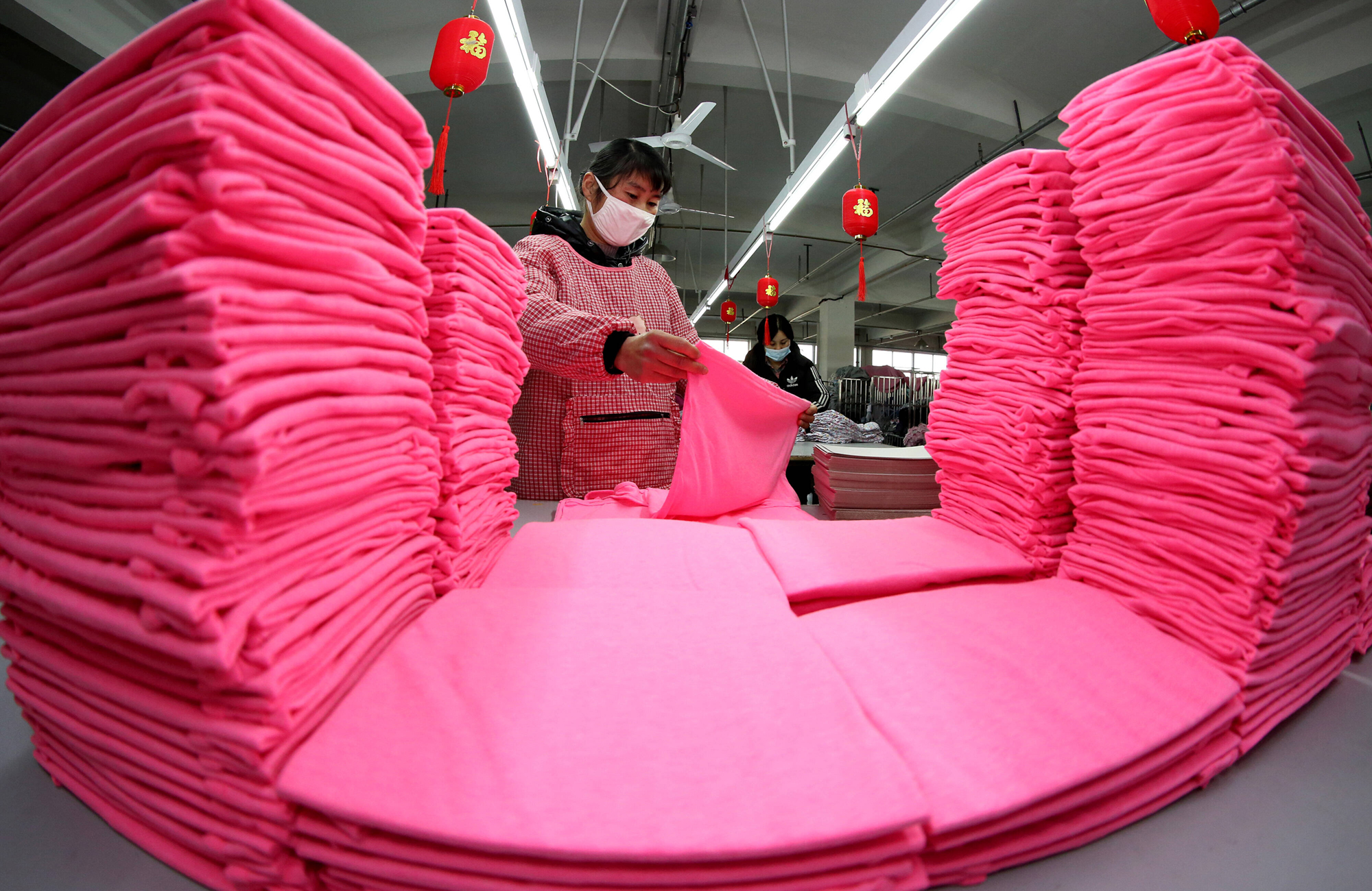 Angestellte in einer Textilfabrik in Zaozhuang (Provinz Shandong) an einer Produktionslinie für Aufträge aus Übersee (Aufnahme vom 17. Februar 2021). In der Textilbranche setzen die Unternehmen ihren Kunden die kürzesten Zahlungsfristen (58 Tage). Foto: IMAGO / VCG